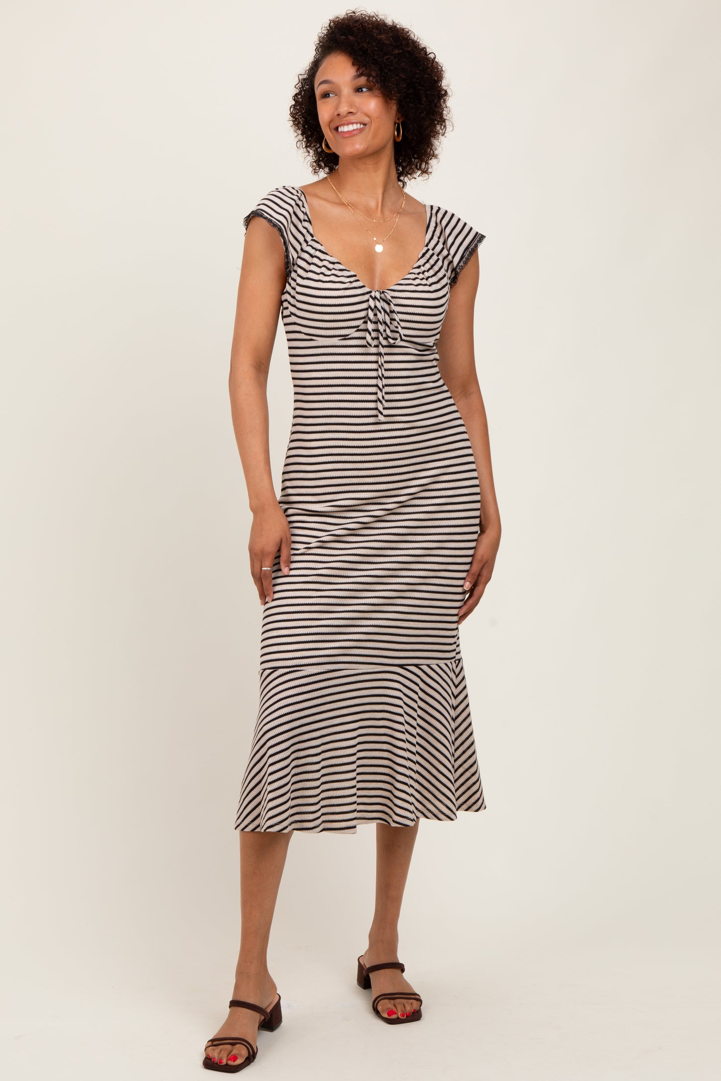 woman wearing a striped midi dress with a tie detail and ruffled hem