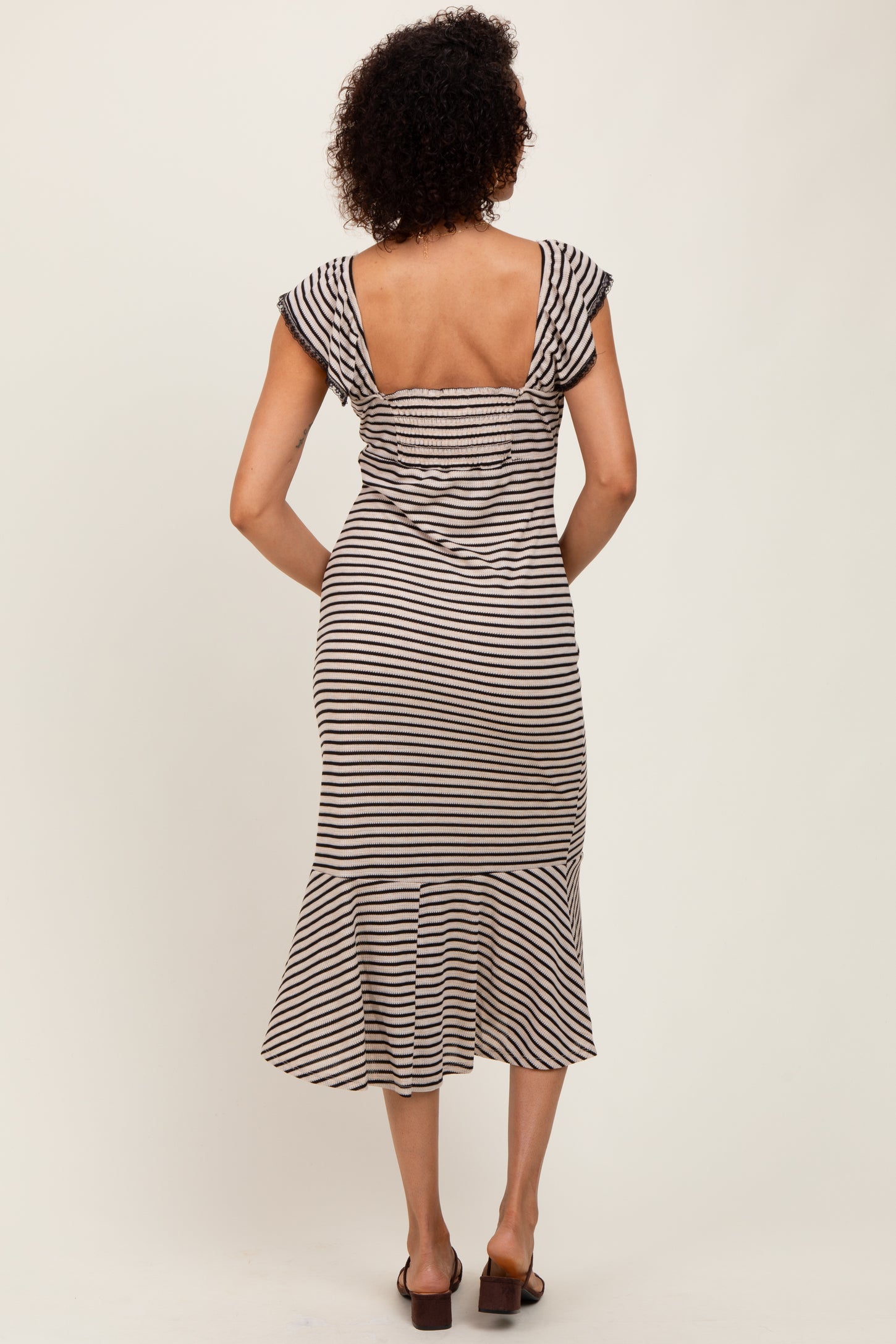 woman wearing a striped midi dress with short sleeves and a flared hem, viewed from the back