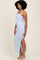 woman wearing a light blue ribbed maxi dress with a side slit and spaghetti straps