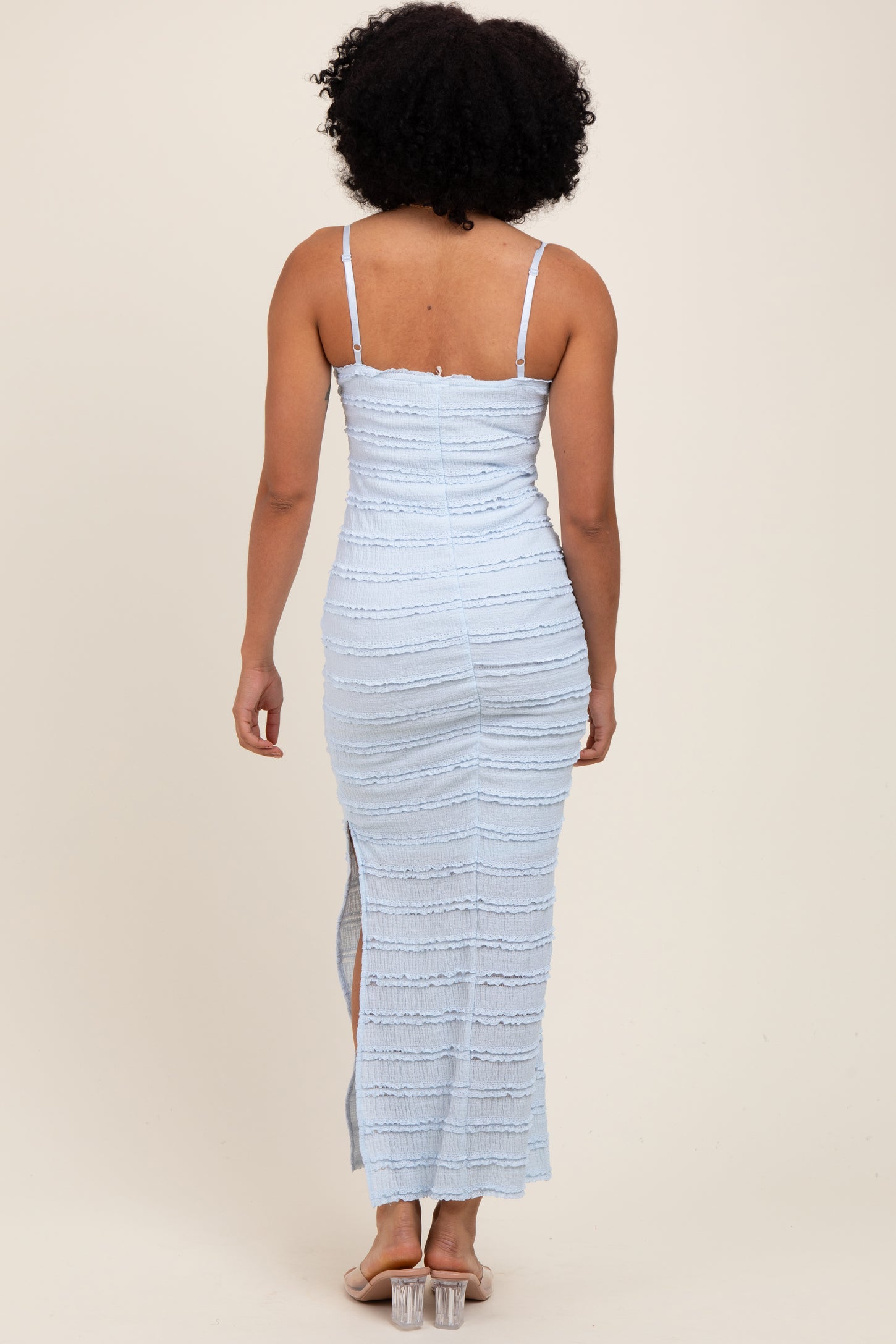 woman wearing a light blue fitted maxi dress with spaghetti straps and side slit, viewed from the back