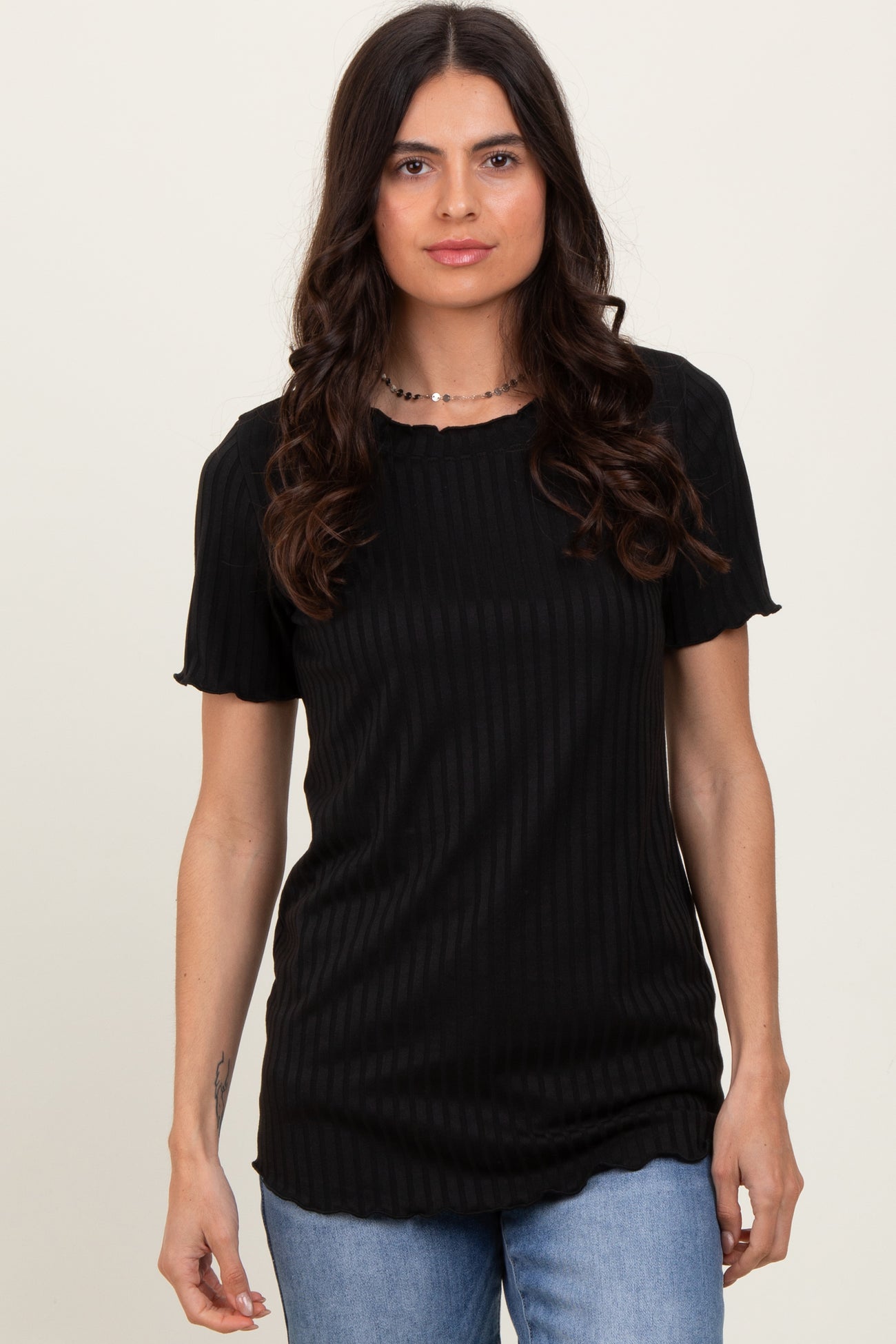 woman wearing a black ribbed short sleeve top with a scalloped neckline and relaxed fit