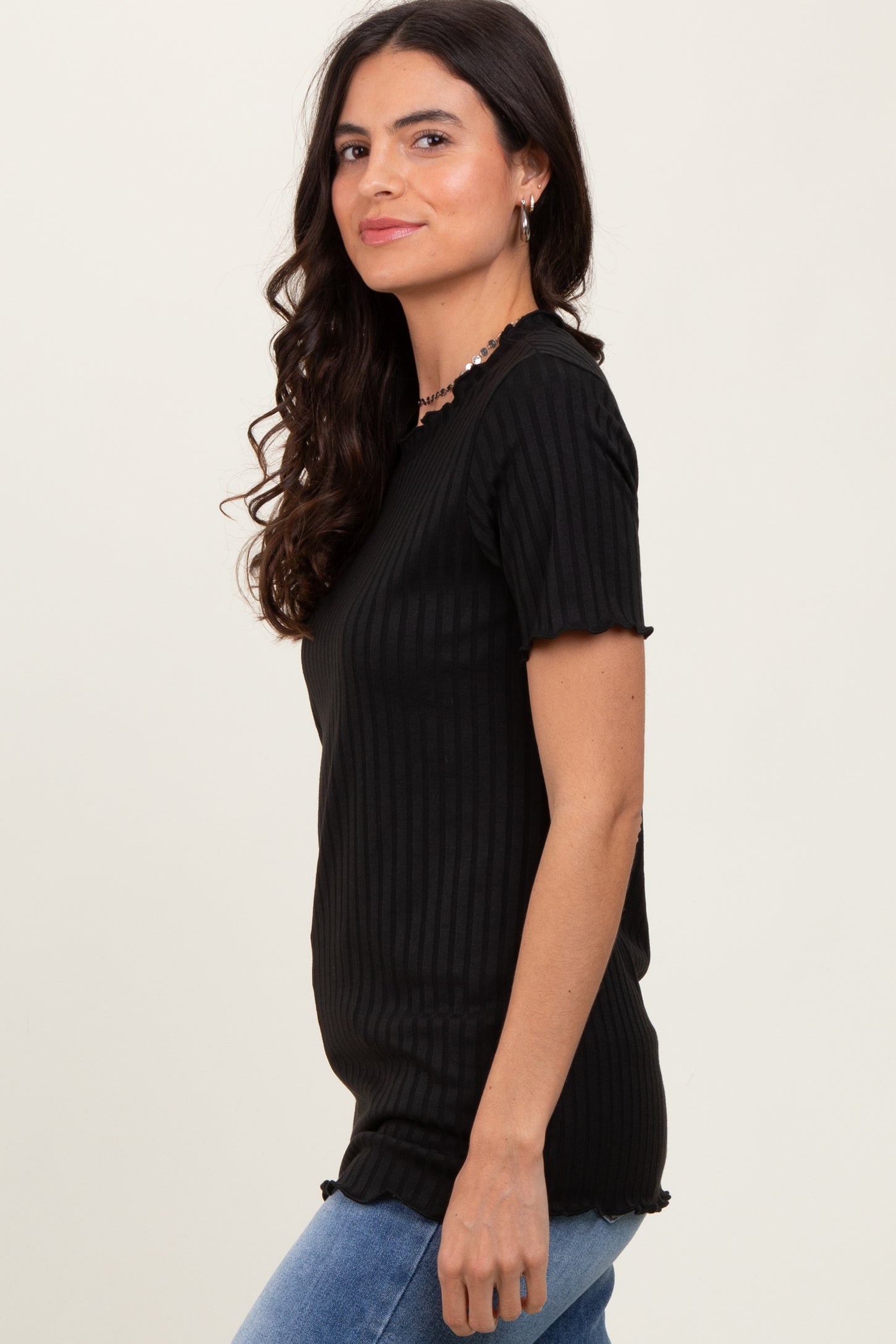 woman wearing a black ribbed short sleeve top with a relaxed fit, paired with blue jeans