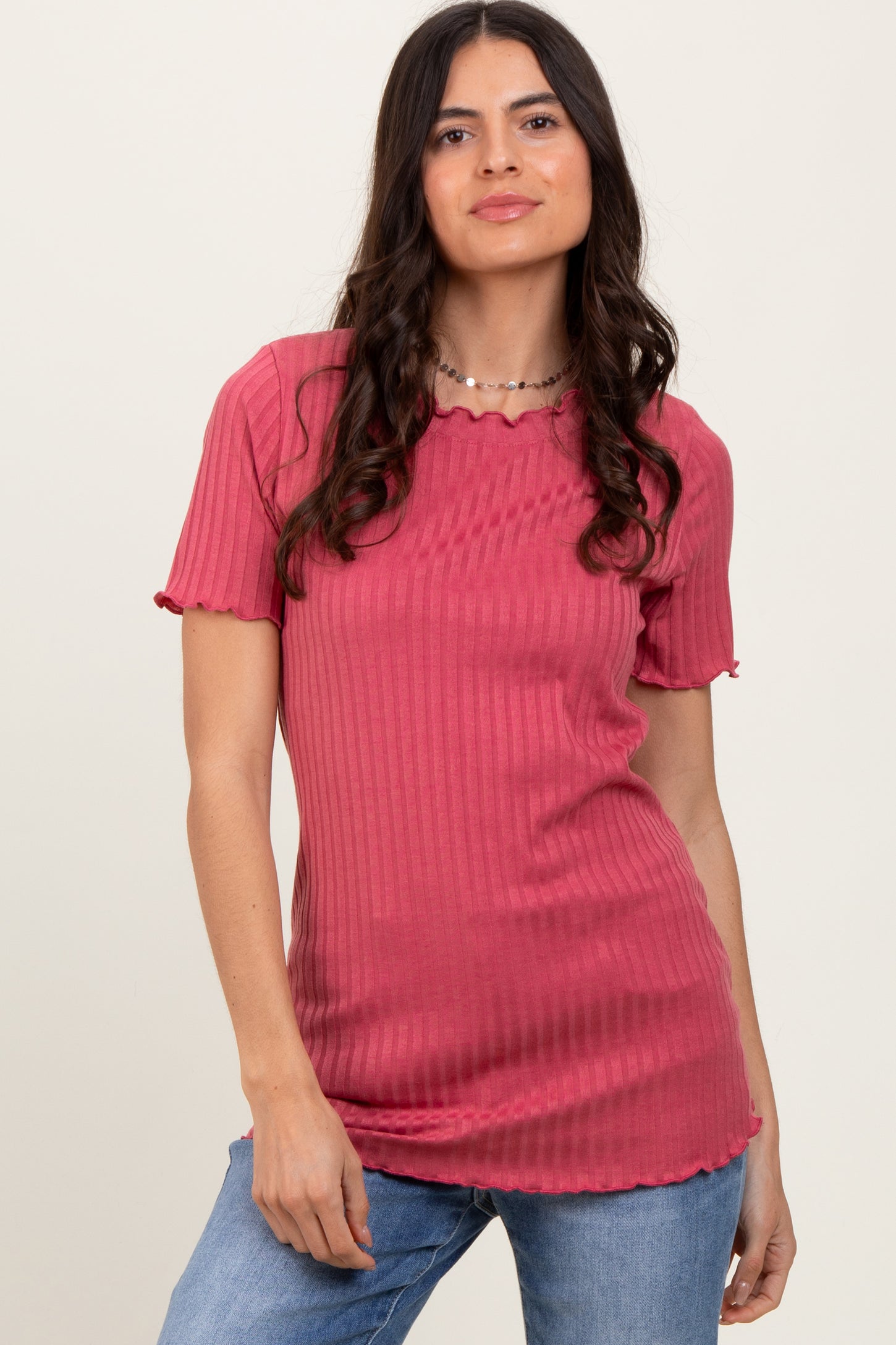 woman wearing a ribbed pink short sleeve top with a scalloped hem and a relaxed fit