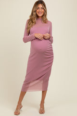 woman wearing a light pink long sleeve maternity dress with side ruching and a visible baby bump