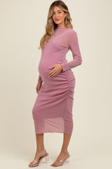 woman wearing a pink long sleeve maternity dress with side ruching and a baby bump visible