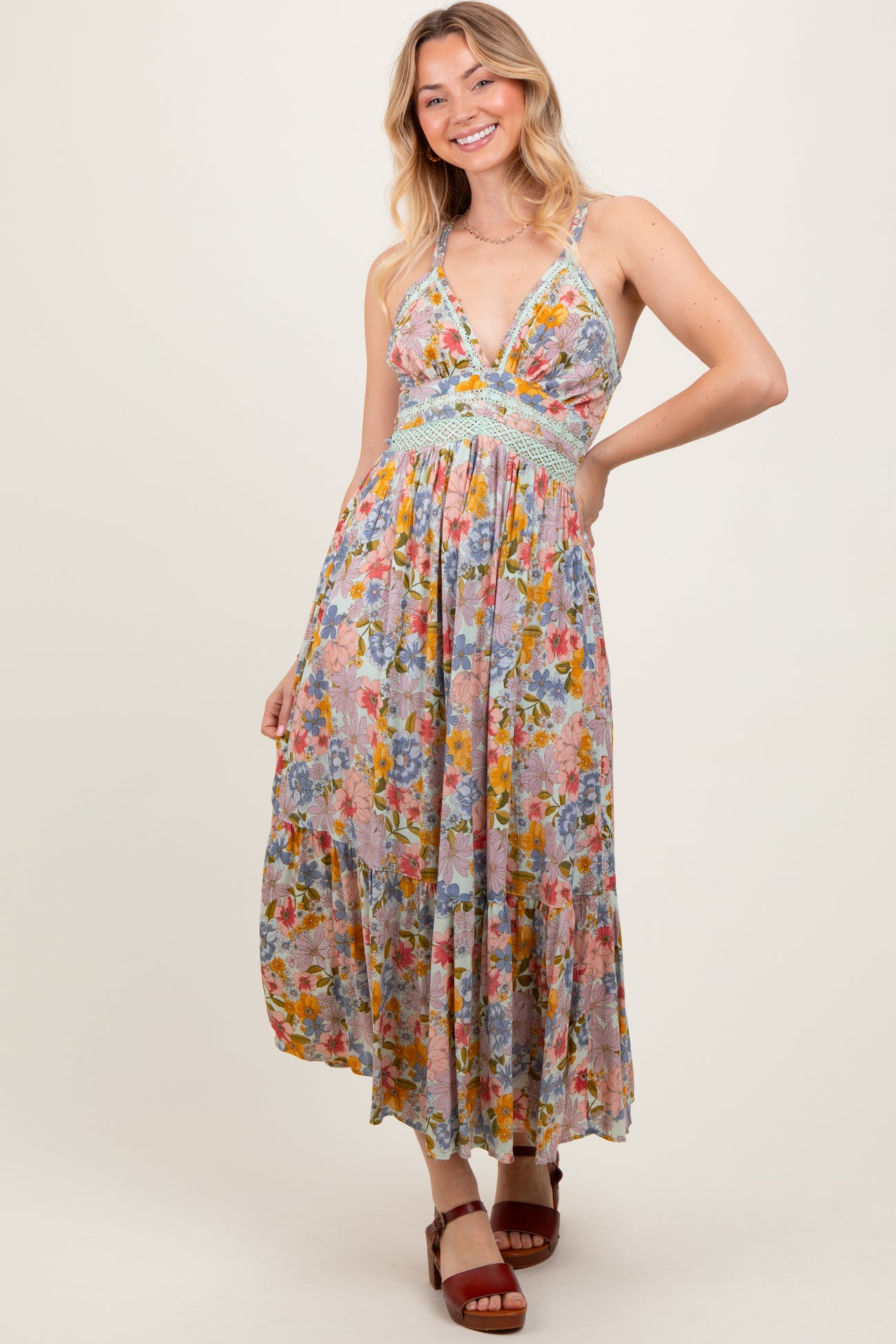 woman wearing a floral print maxi dress with a deep v-neckline and smocked waistband, posing with a smile