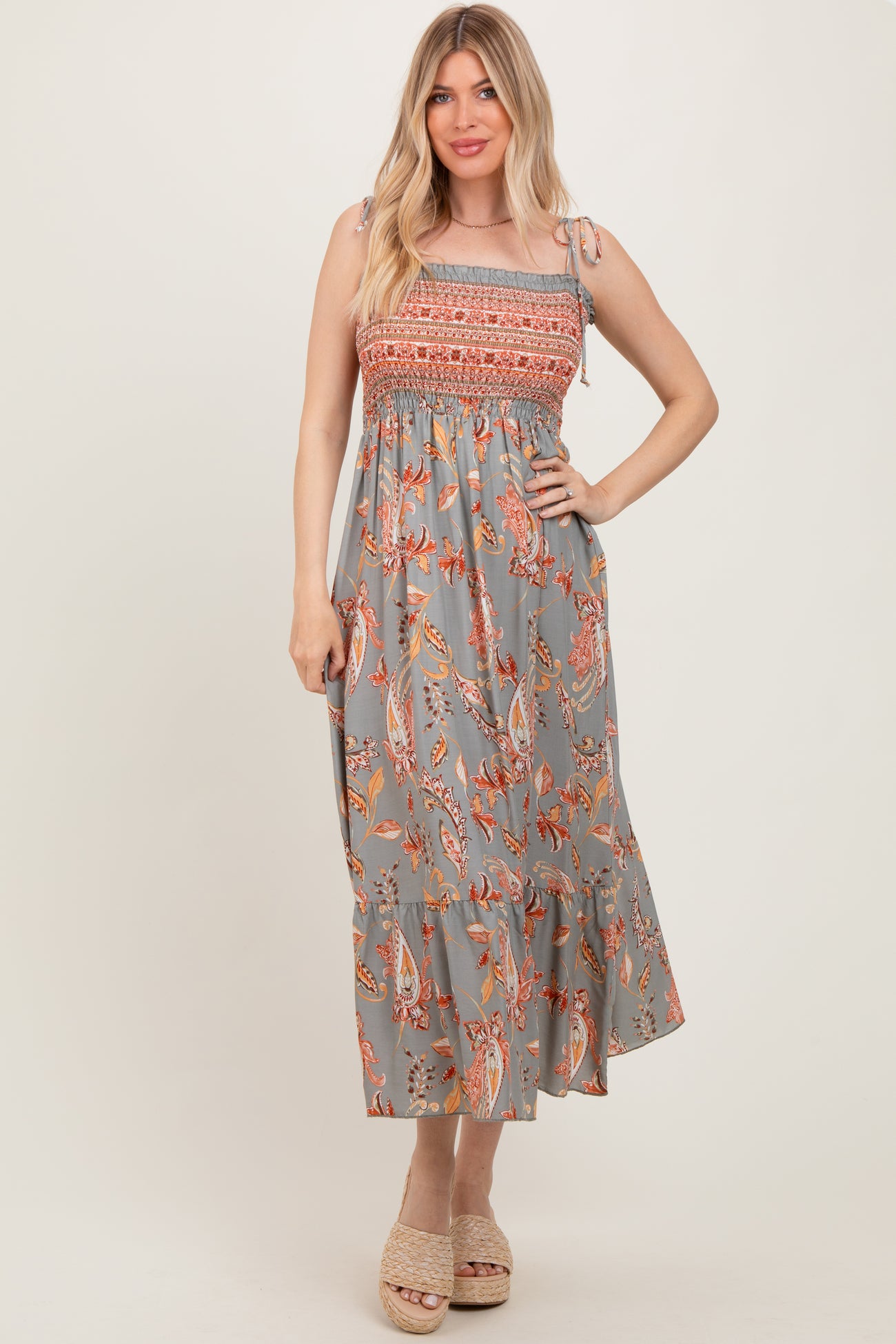 woman wearing a gray floral maxi dress with smocked bodice and tied straps