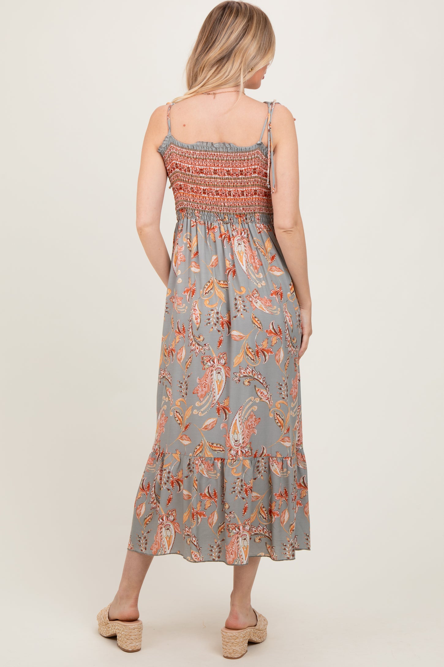 woman wearing a gray floral maxi dress with smocked bodice and ruffled hem, showing the back view