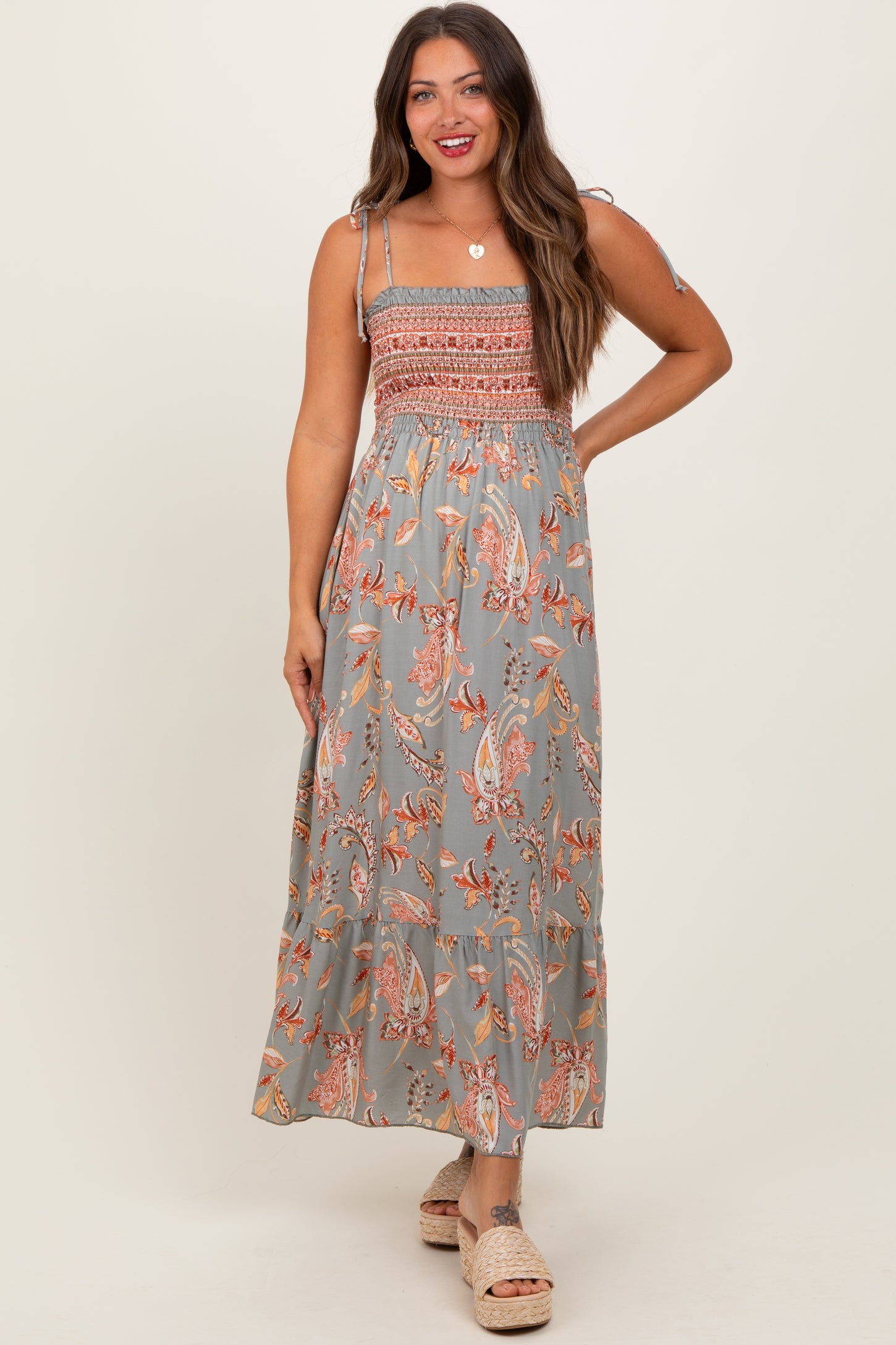 woman wearing a gray floral maternity maxi dress with smocked bodice and spaghetti straps