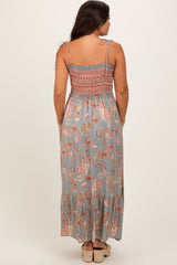 woman wearing a long floral maternity dress with tie straps and a smocked bodice, showing a flowy skirt from the back