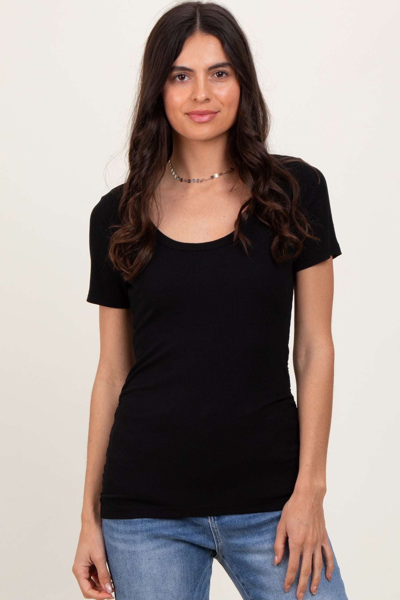 woman wearing a black short sleeve scoop neck top with a fitted silhouette and paired with light blue jeans