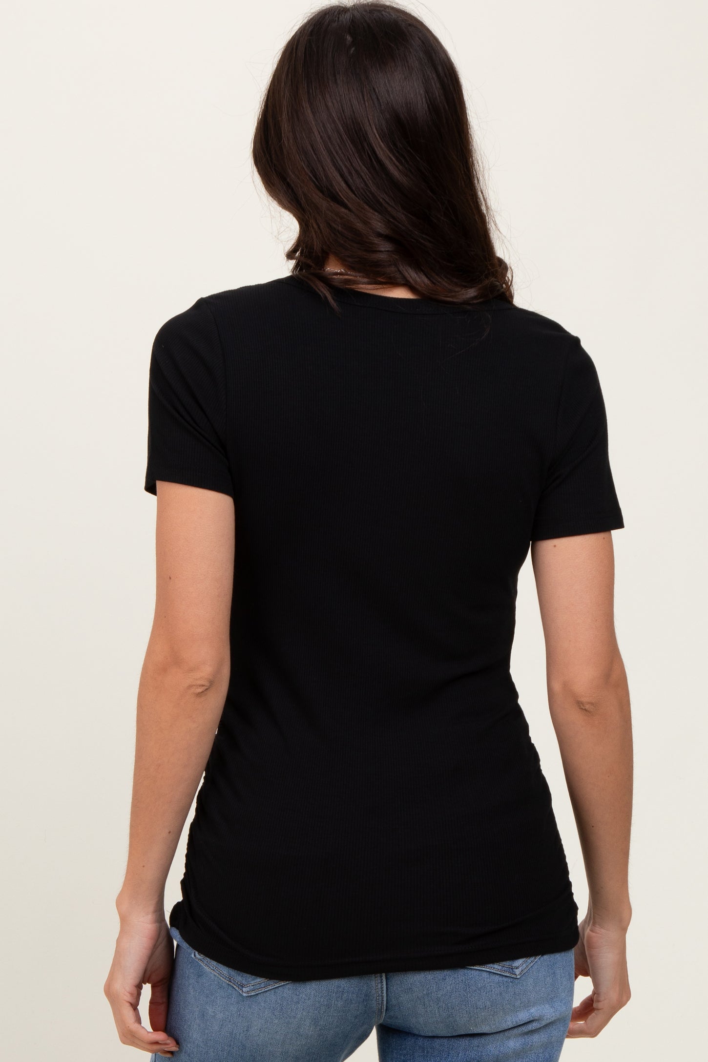 woman wearing a black short sleeve fitted top with a ribbed texture, viewed from the back