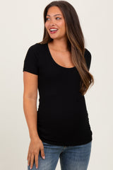 woman wearing a black short sleeve maternity top and showing her baby bump