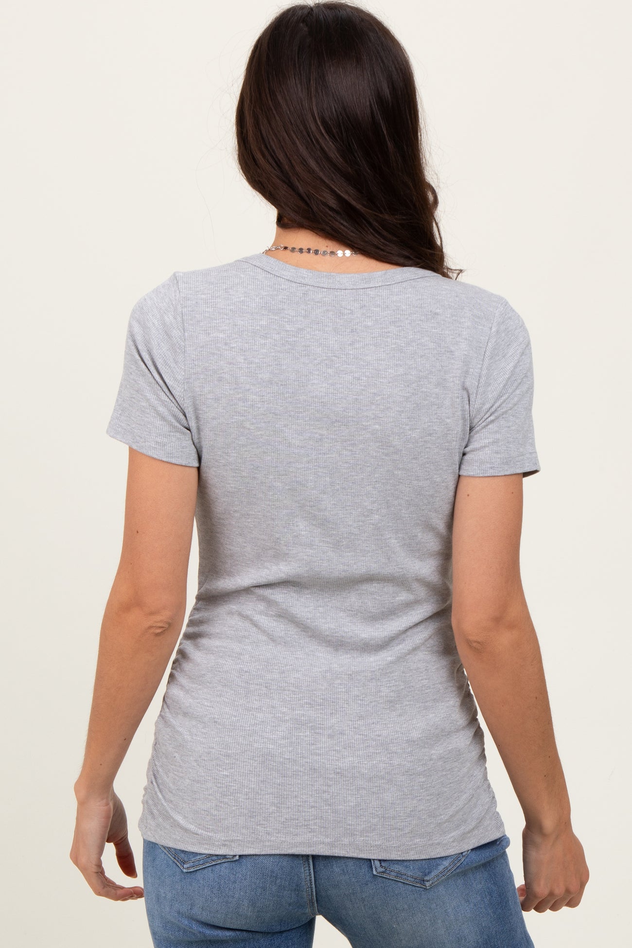 woman wearing a gray short sleeve t-shirt, viewed from the back, paired with blue jeans