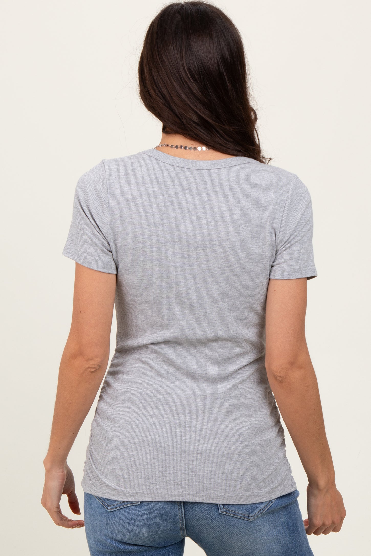 woman wearing a gray short sleeve t-shirt, viewed from the back, paired with blue jeans