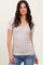 woman wearing a light beige scoop neck short sleeve top paired with blue jeans