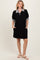 woman wearing a black short sleeve dress with a striped collar and puff sleeves, featuring side pockets