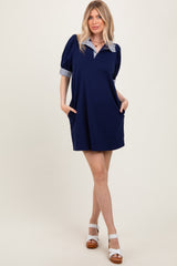 woman wearing a navy short sleeve dress with striped collar and puff sleeves, standing with hands in pockets