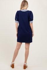 woman wearing a navy blue short sleeve dress with striped collar and sleeves, seen from the back
