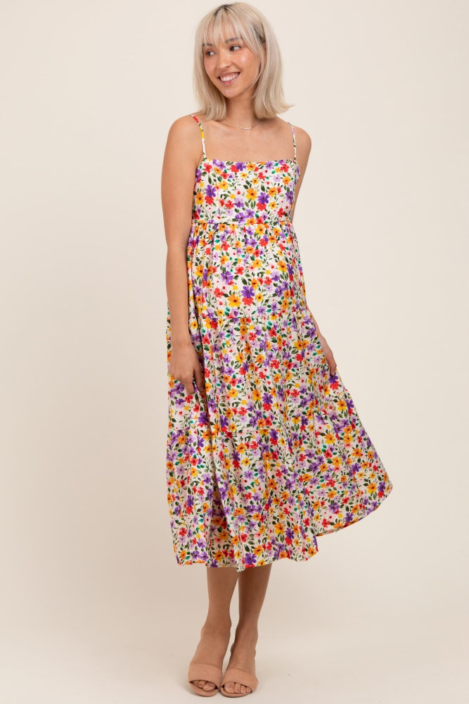 woman wearing a floral maternity dress with spaghetti straps and a flowy silhouette, showcasing her baby bump