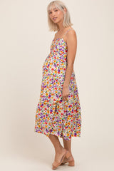 woman wearing a multi-colored floral maternity dress with spaghetti straps and a visible baby bump