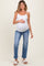 woman wearing a white maternity tank top and light blue maternity jeans, holding her baby bump