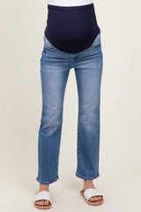 woman wearing light blue maternity jeans with a navy over-the-bump waistband and white sandals