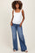 woman wearing a white maternity tank top and relaxed fit blue jeans, showing her baby bump