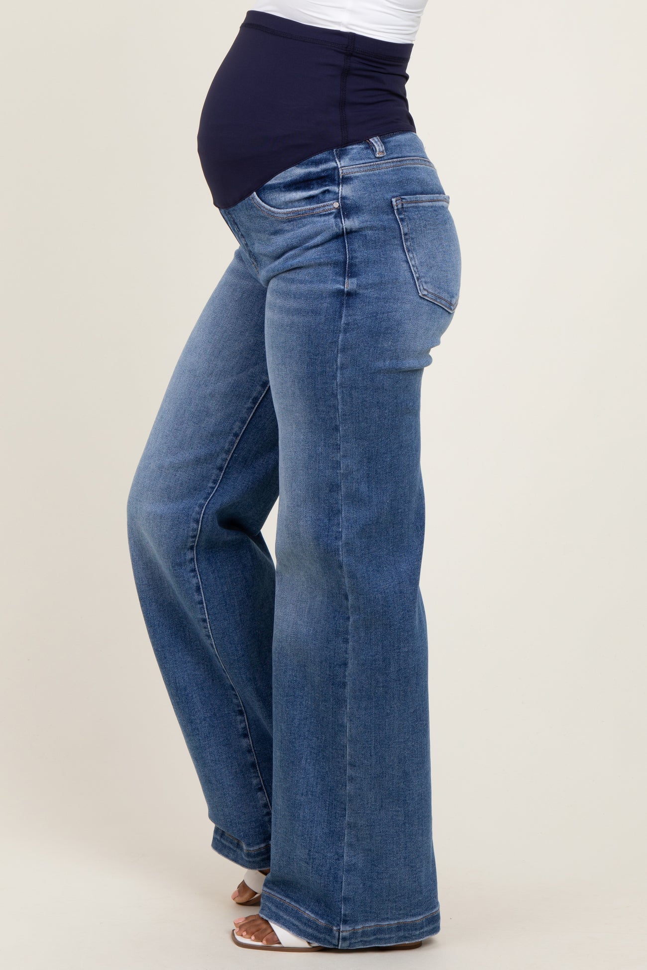 woman wearing a pair of light wash maternity jeans with a wide leg and a supportive waistband, showing her baby bump