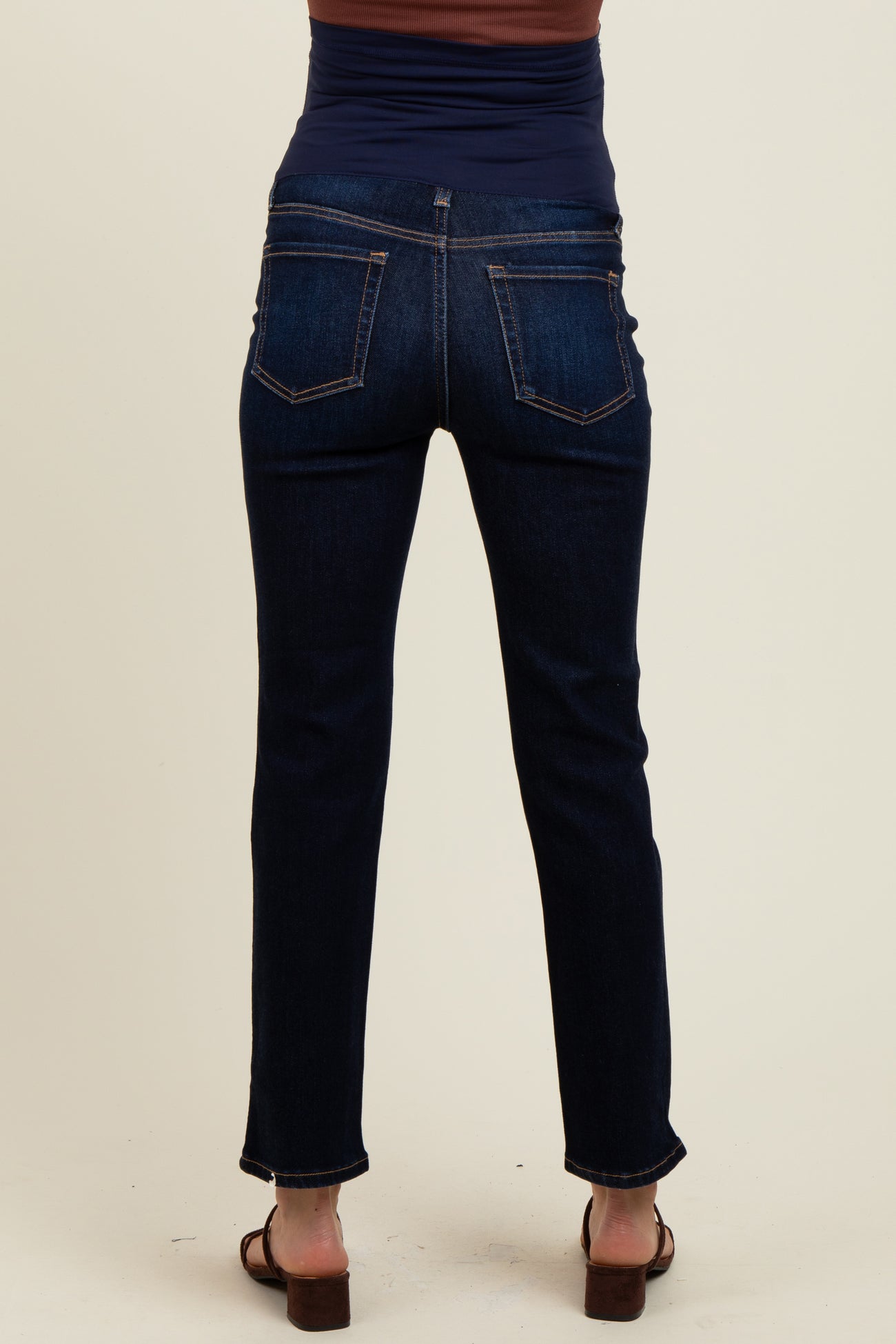 woman wearing dark wash maternity jeans, showing the back view with a fitted waistband and straight leg style