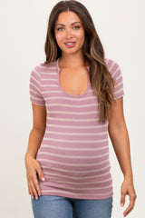 woman wearing a pink and white striped maternity top with a scoop neckline and short sleeves, showing her baby bump