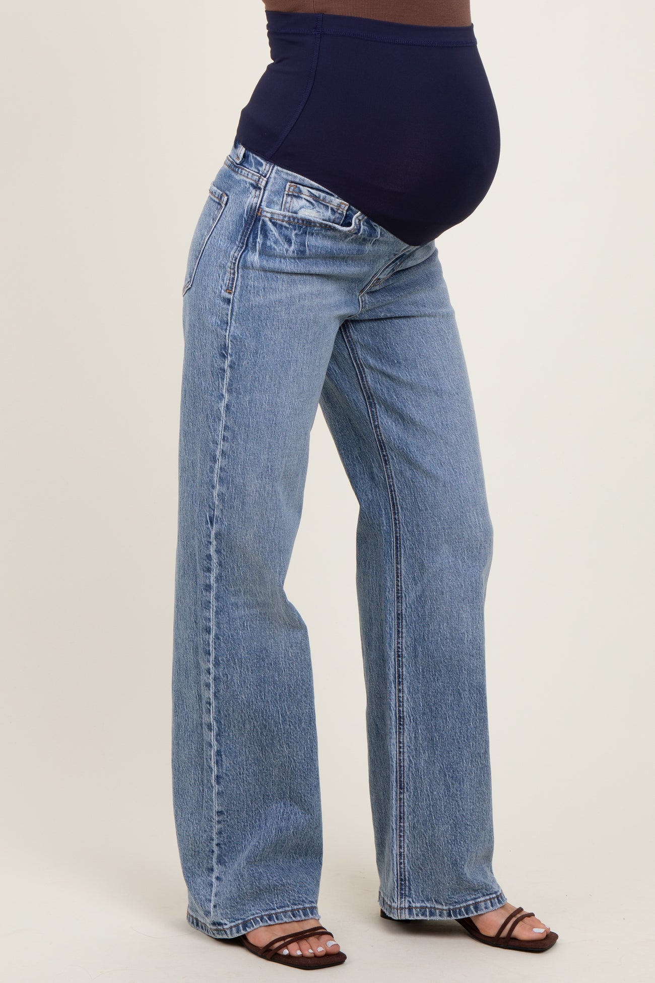 woman wearing a pair of light blue wide-leg maternity jeans and a navy top, showcasing her baby bump