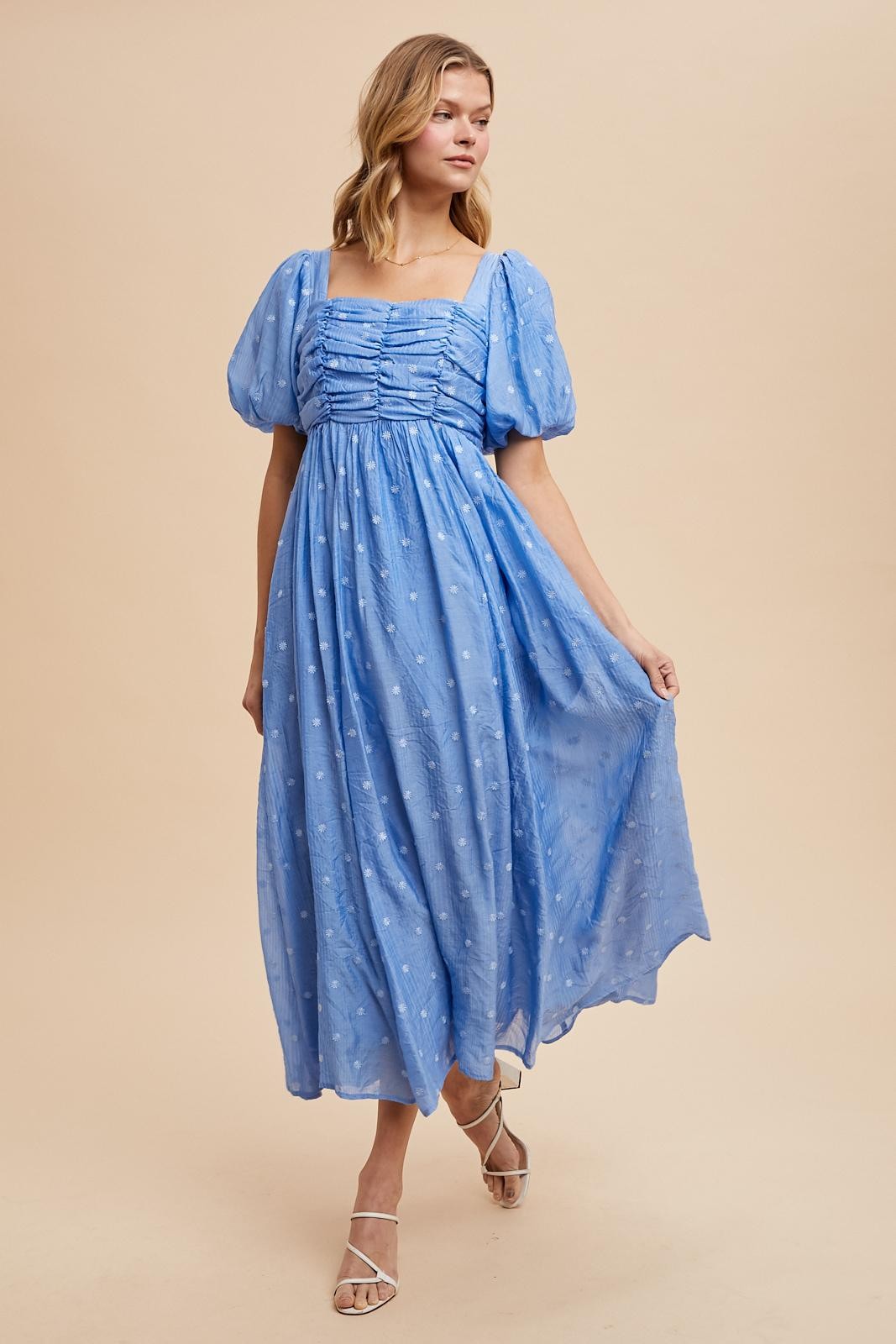 woman wearing a light blue puff sleeve maxi dress with ruched detailing and floral embroidery