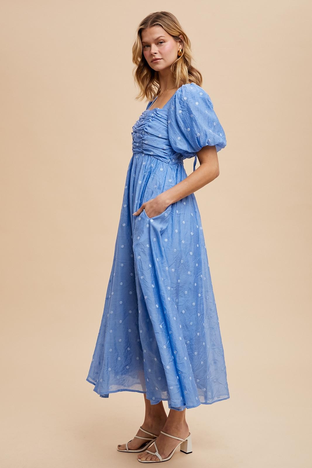 woman wearing a light blue puff sleeve maxi dress with a ruched bodice and pockets, set against a neutral background