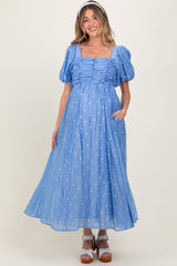 woman wearing a light blue maternity dress with puff sleeves and polka dots, featuring a gathered front and side pockets
