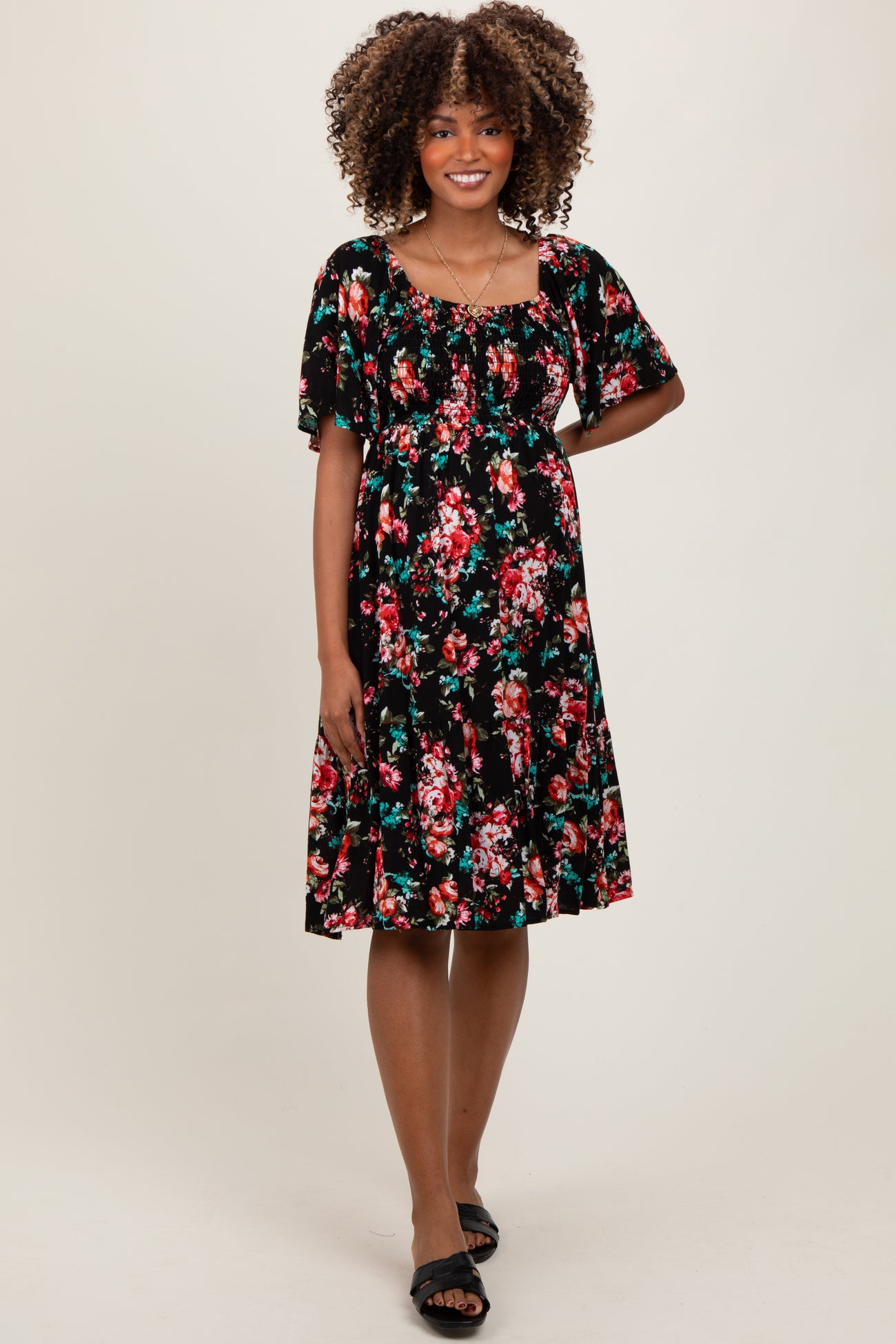 woman wearing a black floral maternity dress with short sleeves and a fitted bodice, showing her baby bump
