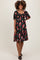 woman wearing a black floral maternity dress with short sleeves and a fitted bodice, showing her baby bump