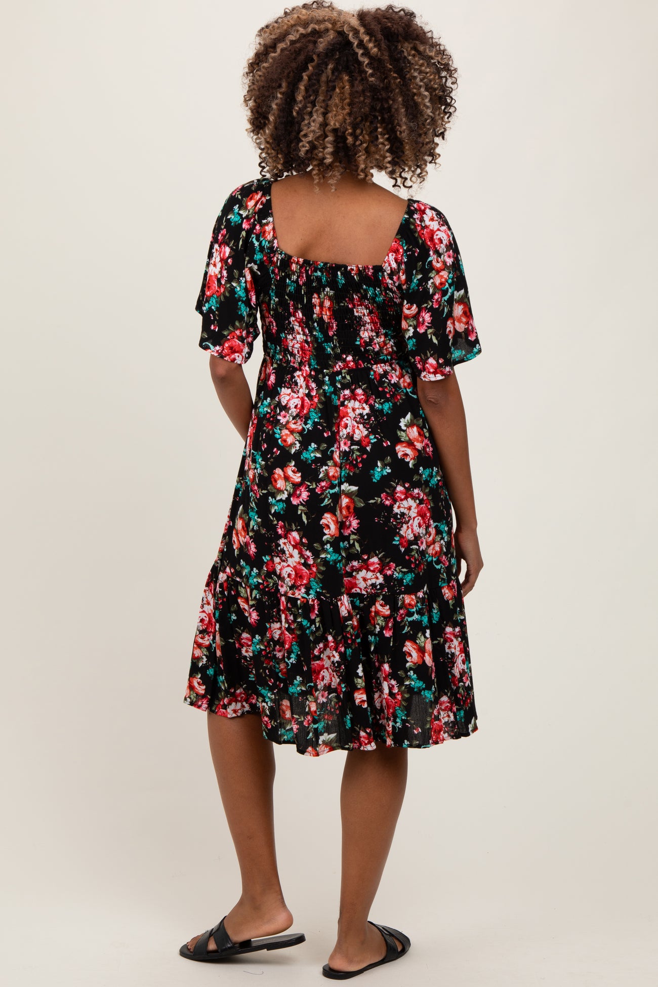 woman wearing a black floral maternity dress with short sleeves and a flared hem