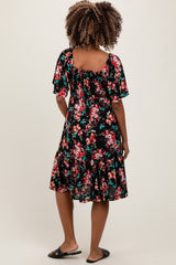 woman wearing a black floral maternity dress with short sleeves and a flared hem