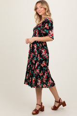 woman wearing a black floral print midi dress with short sleeves and a flared hem, paired with brown heeled sandals