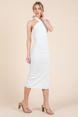 woman wearing a white ribbed midi dress with a halter neck and ruching details, paired with clear strappy heels