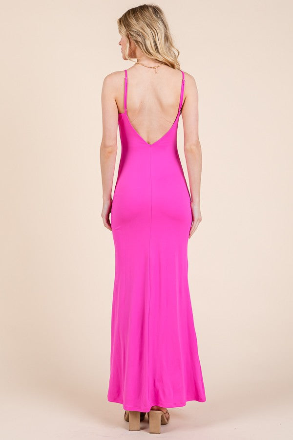 woman wearing a bright pink spaghetti strap maxi dress with a low back