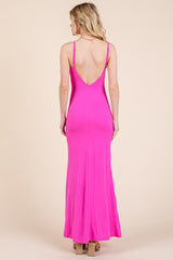 woman wearing a bright pink spaghetti strap maxi dress with a low back