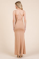 woman wearing a fitted nude maxi dress with a deep V-back and thin straps, showing a sleek silhouette from the back