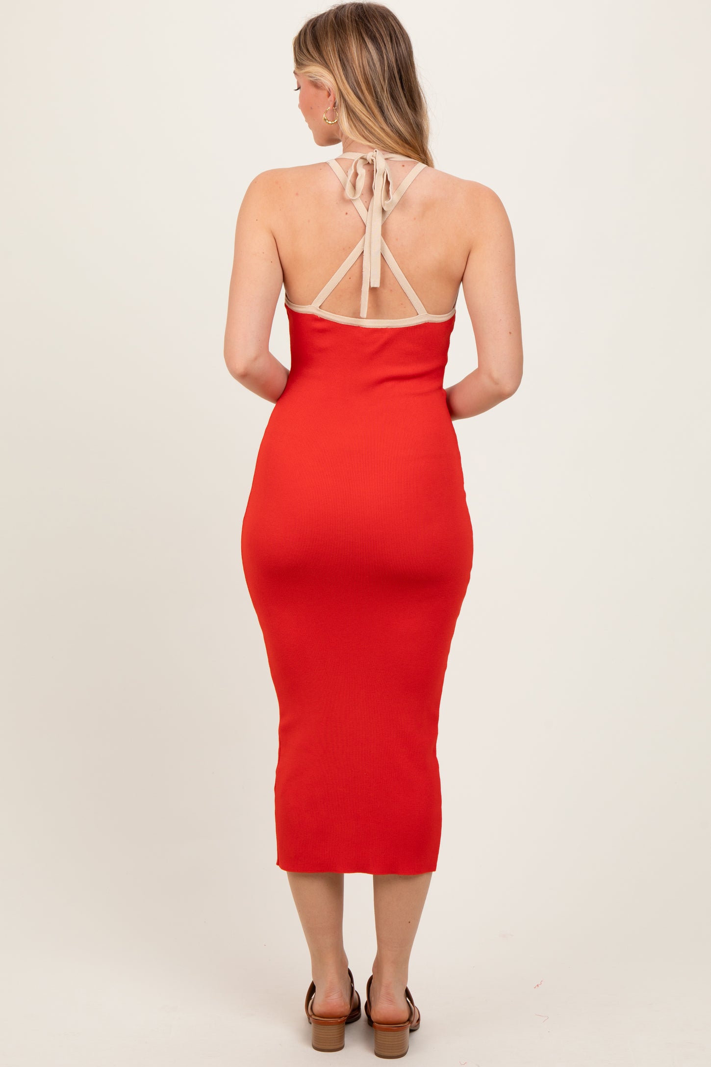 woman wearing a red ribbed midi dress with a halter neck and a fitted silhouette, showing the back view