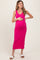 woman wearing a bright pink ribbed maternity dress, cradling her baby bump