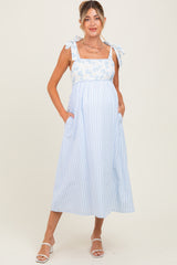 woman wearing a light blue maternity maxi dress with floral print and tie straps, showcasing her baby bump