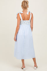 woman wearing a light blue maternity dress with floral details and tie straps, showing a relaxed fit and mid-length style