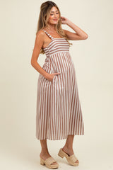 woman wearing a brown and white striped maternity dress with pockets and a visible baby bump