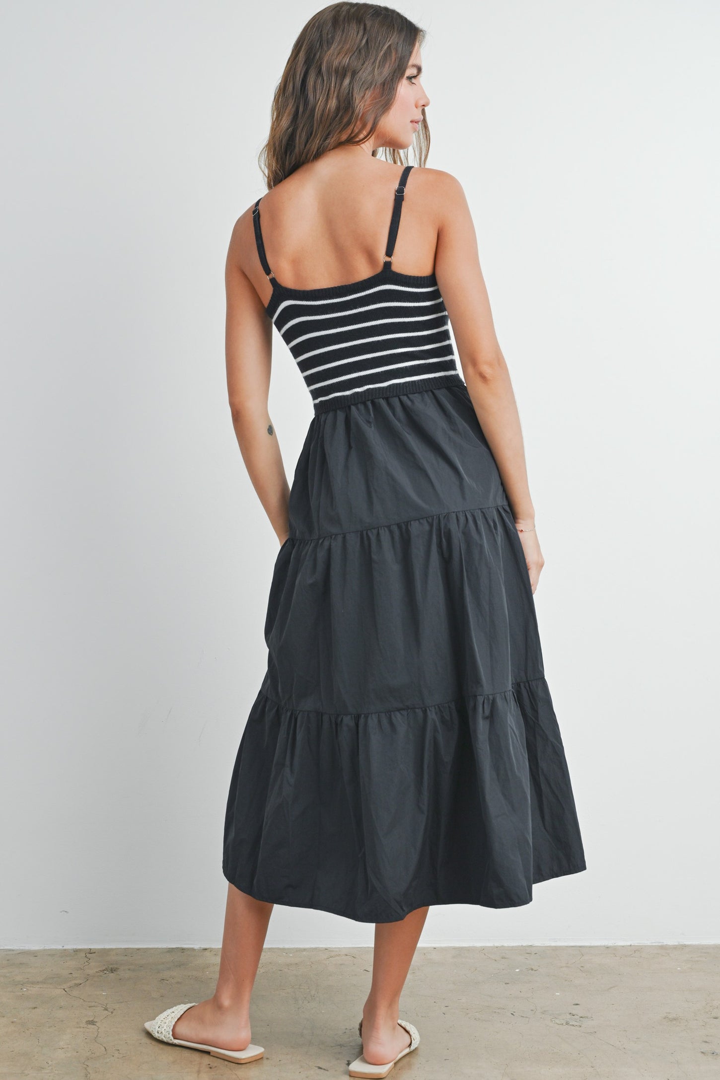 woman wearing a black and white striped sleeveless maxi dress with tiered skirt and spaghetti straps